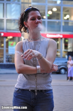Brunette babe smoking while loitering on the street