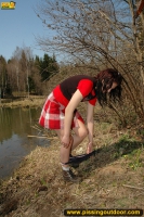 Outdoor pissing on the dry grass on a pond shore