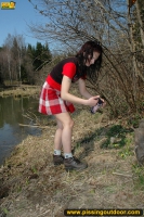 Outdoor pissing on the dry grass on a pond shore